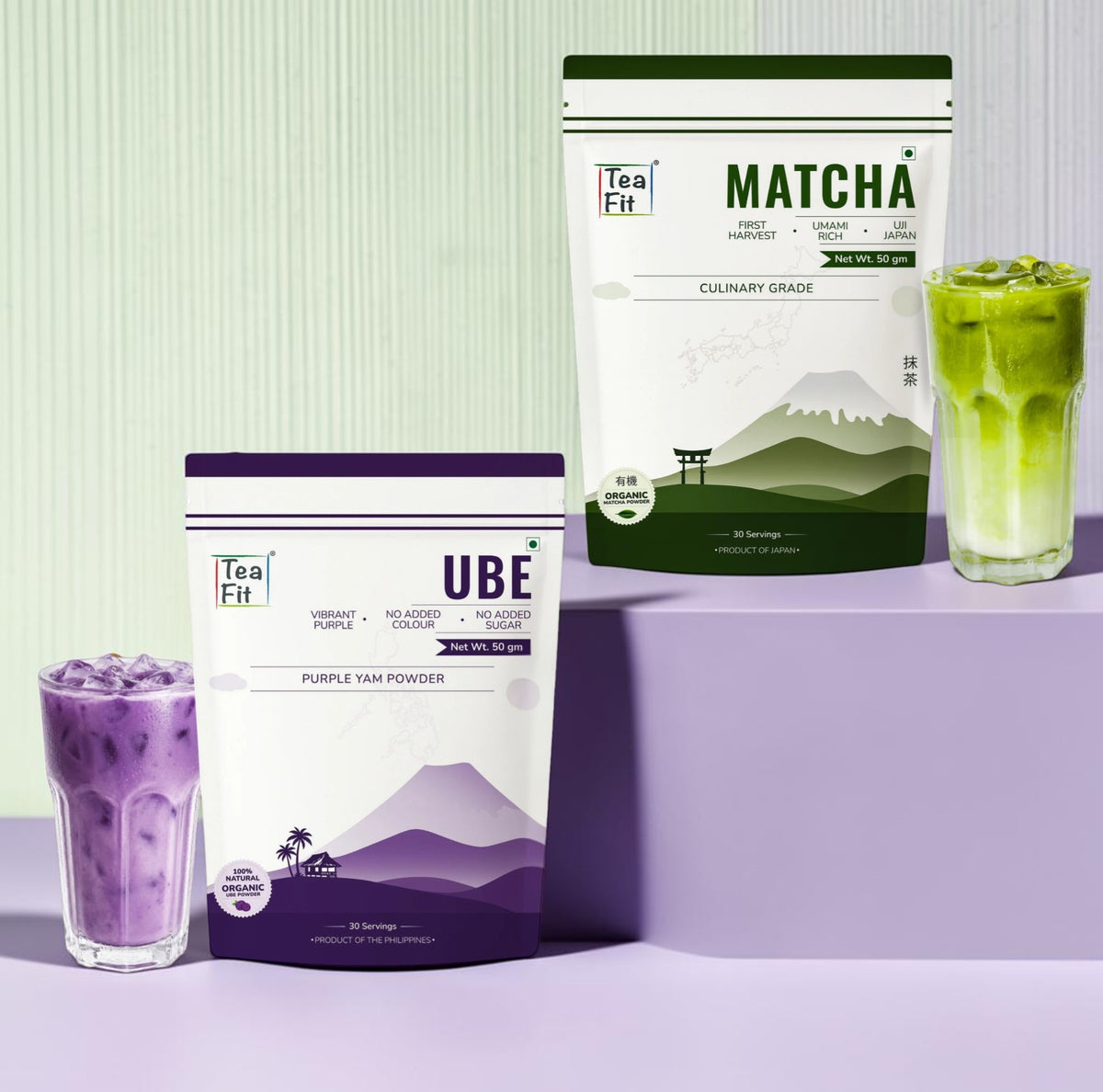 Two stand-up pouches of Tea Fit Culinary Matcha powder and UBE , displayed with iced drinks in glasses on a purple and light green studio set.