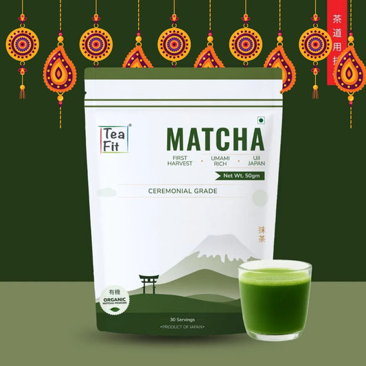 A stand-up pouch of Tea Fit Matcha Ceremonial Grade tea with a small glass of green matcha tea in front, set against a dark green background with decorative hanging ornaments and a red vertical banner.