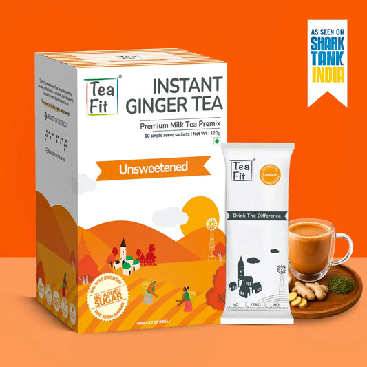 Tea Fit Instant Ginger Tea Premium Milk Tea Premix box and single-serve packet on an orange background, with a cup of ginger tea, ginger root, and green powder on a wooden tray, plus an 'As seen on Shark Tank India' badge.