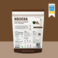A stand-up pouch of 'Hojicha Naturally Vibrant Low Caffeine' tea by 'As Seen on Shark Tank India', shown against a solid brown background. The packaging is primarily white with dark brown borders at the top and bottom, featuring product details, nutritional facts, and a barcode on the lower half.