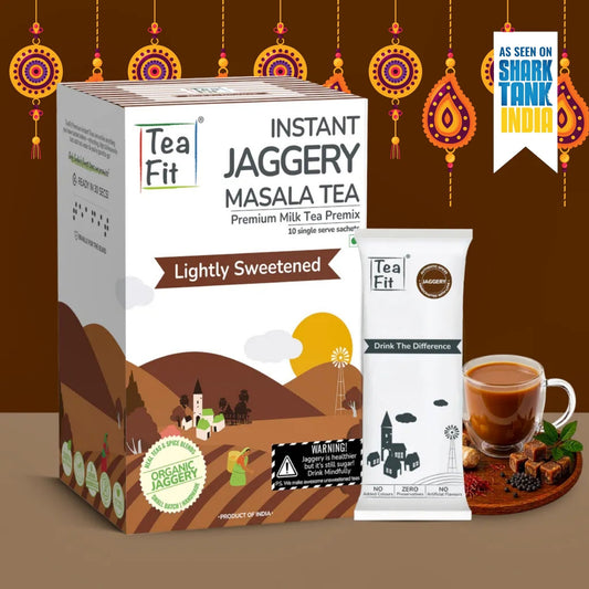 Tea Fit Instant Jaggery Masala Tea packaging shown with a box, sachet, and a cup of tea on a brown background with decorative hanging ornaments and a Shark Tank India badge.