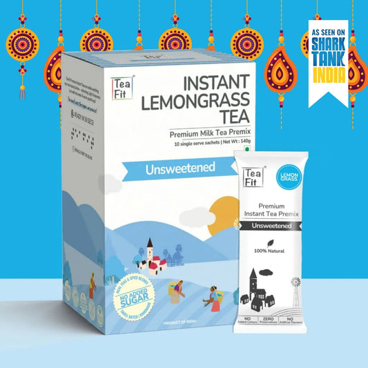 Tea Fit Instant Lemongrass Tea Premium Milk Tea Premix box and single sachet shown on a bright blue background with decorative hanging ornaments and a badge reading 'As seen on Shark Tank India'.