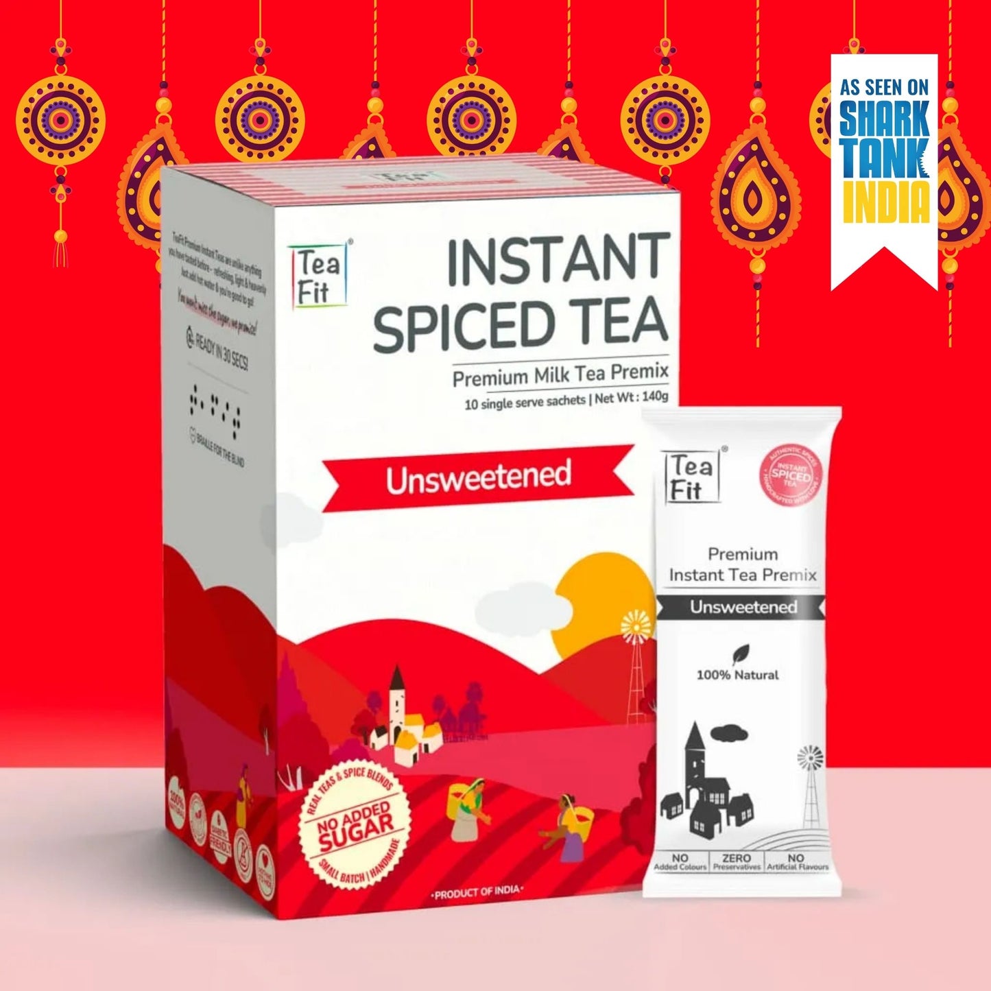 Tea Fit Instant Spiced Tea Premium Milk Tea Premix box and single serve sachet, shown on a bright red festive background with decorative hanging ornaments and a Shark Tank India badge.