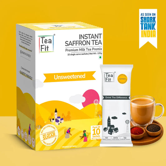 Tea Fit Instant Saffron Tea Premium Milk Tea Premix box and single sachet shown on a yellow background, with a cup of milk tea and small bowls of spices beside it. A badge in the top right says it has been seen on Shark Tank India.