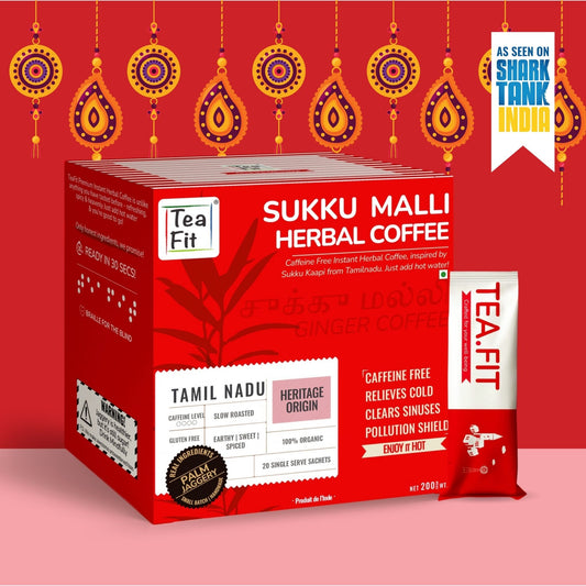 A red box of Tea Fit Sukku Malli Herbal Coffee with a single sachet in front, shown on a pink background with decorative hanging motifs and a badge reading 'As seen on Shark Tank India'.